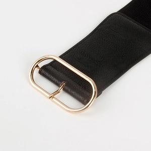 Close-up of black textured leather wide belt featuring a polished gold oval metal buckle