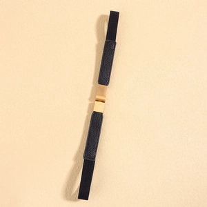 Detail of black elastic waist belt featuring a gold matte buckle and lychee leather trim