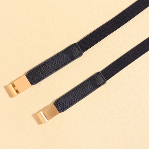Detail of black elastic waist belt with gold buckle and textured leather connectors