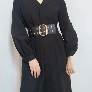 Detail of wide black waist belt with large gold square buckle and eyelets on dress