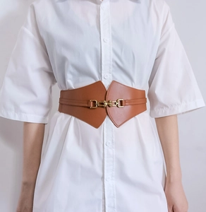 Macro detail of brown leather corset belt featuring a gold metal horsebit buckle closure