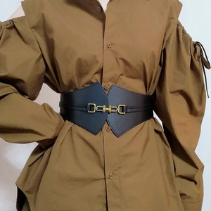 Detail of black corset belt with gold clasp on brown shirt showing slim fit silhouette