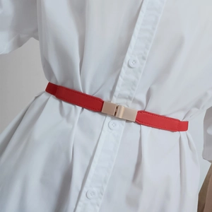 Detail of red thin leather belt with gold rectangular buckle on white shirt