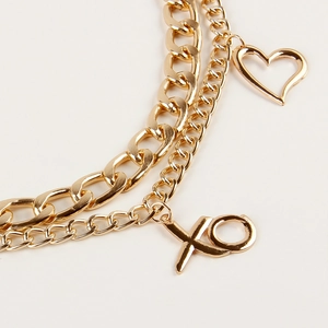 Detail of gold layered waist chain featuring elephant, heart charms and XO lettering