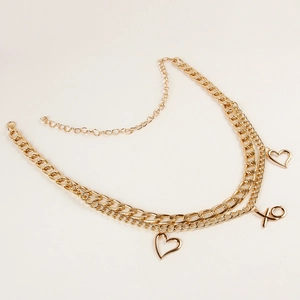 Detailed macro view of gold multi-layer belt chain with heart and XO letter pendants