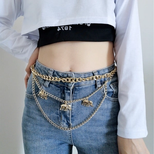 Detail of gold multi-layered metal waist chain with elegant elephant charms on denim