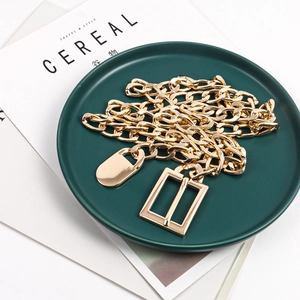 Detail of chunky gold Cuban link waist chain with metal buckle on a green plate