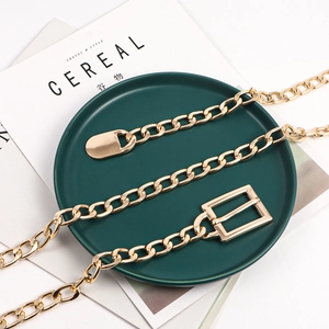 Polished gold metal chain belt with rectangle buckle displayed on elegant tray