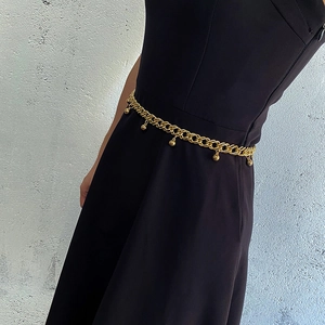 Détail d'une chaîne de taille dorée à double rangée avec perles sur robe noire