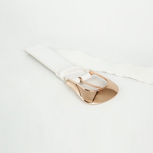 Detalle de la hebilla de metal oro rosa y la textura elástica blanca del cinturón ancho