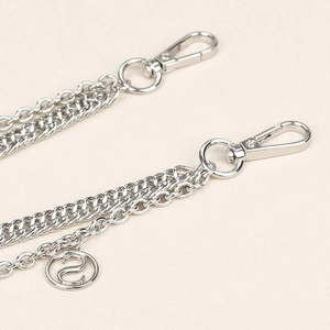 Détail d'une chaîne de pantalon double en métal argenté avec fermoirs et pendentif lettre S
