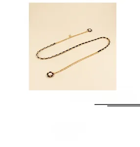 Detail view of woven golden metal chain with black leather and white pearl camellia charms