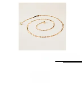 Détail d'une chaîne de taille en métal doré avec anneaux ovales et pendentifs boules