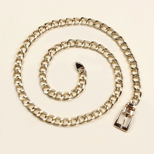 Detailed view of polished gold metal chain belt with square buckle and tapered tip