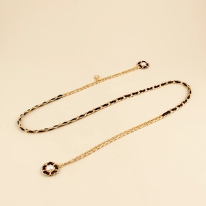 Detailed view of woven metal and leather waist chain with camellia pearl charms