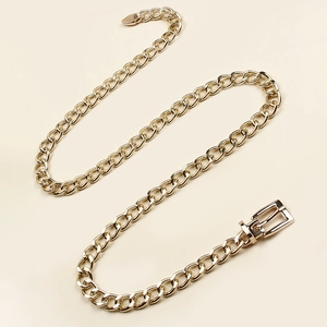 Detail of gold metal link waist chain featuring a heart pendant and pin buckle closure