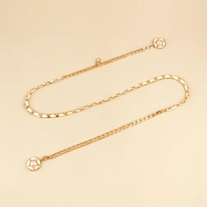 Detail shot of golden metal waist chain with flower motifs and white faux pearl centers