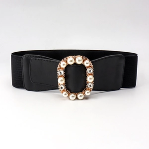 Detail of a wide elastic belt featuring an oval buckle with large pearls and sparkling rhinestones
