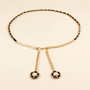 Close-up of woven gold metal waist chain with black ribbon and pearl flower charms