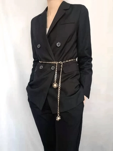 Detail of gold metal waist chain with camellia pendants on a black blazer