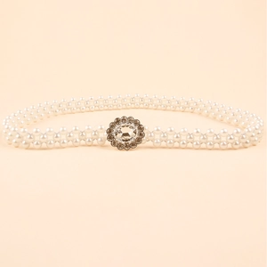 Close-up of woven pearl belt featuring a sparkling rhinestone-encrusted metal flower clasp