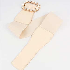 Macro detail of elastic cream waist belt with rhinestone and pearl buckle decoration