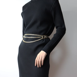 Détail d'une chaîne de taille dorée à trois épaisseurs avec trois anneaux sur une robe noire