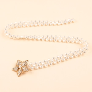 Detail of woven pearl belt featuring a sparkling star-shaped buckle with rhinestones