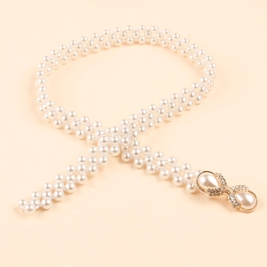 Detail of woven pearl waist belt with gold bow buckle and sparkling rhinestones