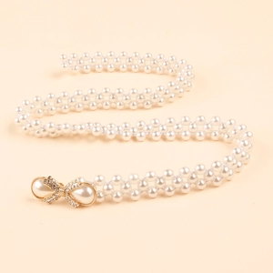 Detail of woven pearl belt featuring a golden rhinestone bow buckle for elegant dresses