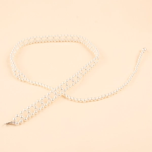 Detailed view of woven pearl waist chain with hollow net design and metal lobster clasp
