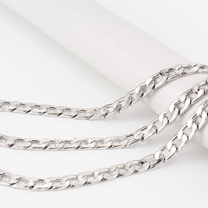 Gros plan détaillé d'une ceinture triple chaîne gourmette argentée sur support blanc