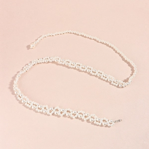 Detail of woven faux pearl belt featuring intricate mesh texture and secure lobster clasp