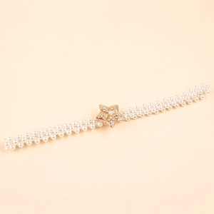 Close-up of woven pearl belt featuring a gold star buckle with sparkling rhinestones