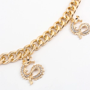 Detail of gold Cuban chain waist belt featuring twin dragon pendants with white rhinestones