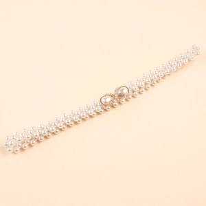 Detail of woven pearl belt featuring a golden bow buckle with rhinestones and pear drops
