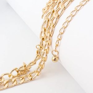 Detail of layered gold metal waist chain featuring a dragon totem and round pendant