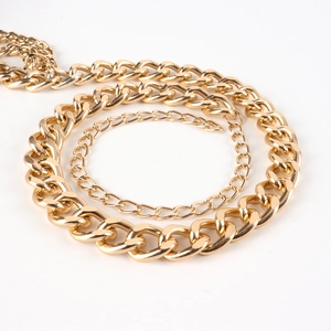 Detail view of golden three-layer chain belt with polished metal finish and curb links