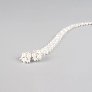 Detail van elegante parelmoer tailleketting met zilveren bloemgesp op grijze basis