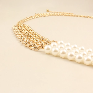 Detail view of golden triple-layer metal chain belt with elegant rows of white pearls
