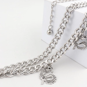 Detail of silver link chain belt featuring intricate dragon pendants with sparkling crystals