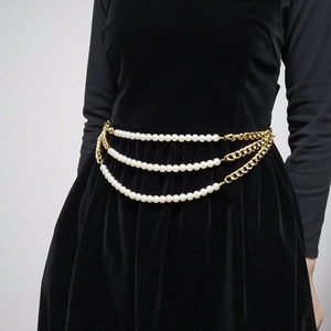 Close-up of triple-layer pearl and gold chain waist belt on a black velvet dress