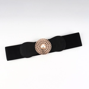 Détail d'une boucle filigrane or rose avec perle sur une ceinture élastique noire