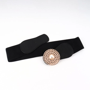 Détail d'une ceinture corset élastique noire avec boucle en métal doré et perle