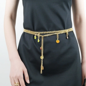 Détail de la chaîne de taille argentée avec des breloques de fruits sur une robe noire