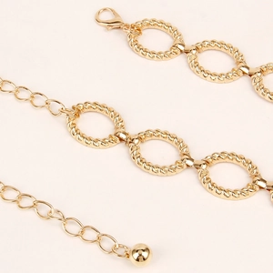 Detail of golden metal waist chain with twisted oval links and adjustable lobster clasp