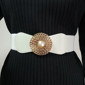 Détail d'une ceinture large élastique blanche avec boucle dorée ajourée et perle centrale