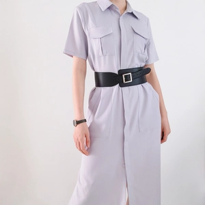 Détail d'une large ceinture noire en cuir avec boucle carrée argentée sur robe mauve
