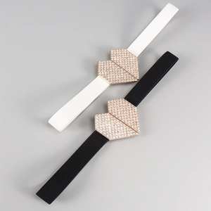 Détail des boucles cœur en strass dorés sur des ceintures élastiques noires et blanches