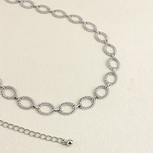 Detail shot of textured silver twisted oval link belt chain with a metallic bead drop